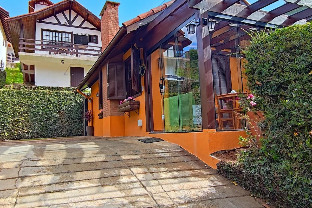 A residential property with a covered porch, a brick chimney, and a glass door leading to a garden area.