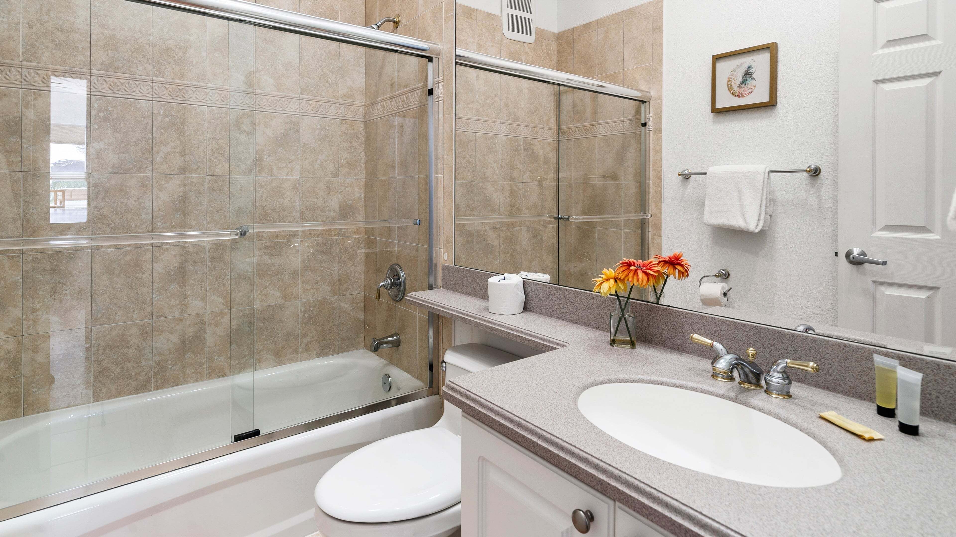 Un bagno con doccia vetro, un water bianco, un lavandino con specchio e un porta asciugamani.