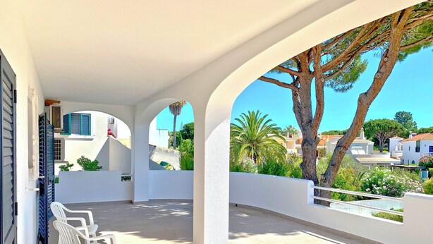 A covered outdoor area with a tiled floor, white walls, and a view of surrounding buildings and trees. - Old Village area, Your Perfect Vilamoura Getaway, Private Pool, Free AC & Wifi (Vilamoura)