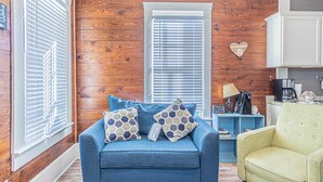 Un salon chaleureux avec un canapé bleu, des murs en bois et un décor en forme de cœur accroché au mur.