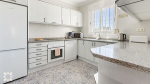 A modern kitchen with white cabinetry, a granite countertop, a built-in oven, a microwave, and a coffee maker. - Villa MACKAY by Abahana Villas (Calpe)