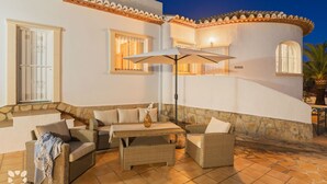 An outdoor seating area with wicker furniture, a table, and a large umbrella. - Villa MACKAY by Abahana Villas (Calpe)
