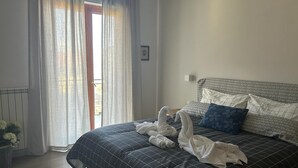 A hotel room with a bed, a radiator, a window with curtains, and an air conditioning unit. - Casa Raffaella - Apartment 2 (Pimonte)