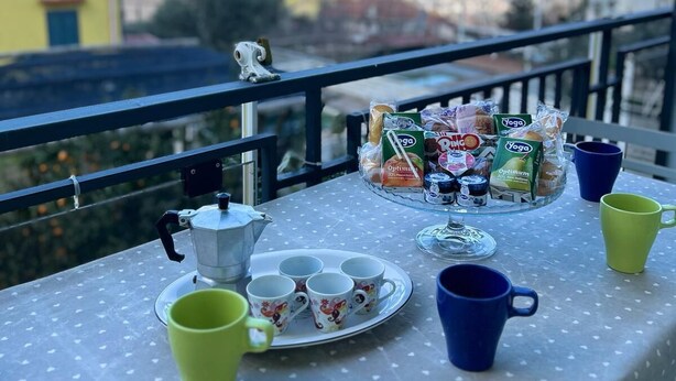 A balcony table with a polka dot tablecloth, a coffee pot, cups, and a snack tray with yoga and energy bars. - Casa Raffaella - Apartment 2 (Pimonte)