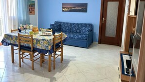 A dining area with a table set for four, a sofa, and a door with a frosted glass panel. - Casa Raffaella - Apartment 2 (Pimonte)