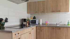 Una cocina con armarios de madera, microondas, cafetera y un lavabo.