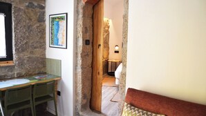 A stone wall, a wooden door, a map on the wall, a small table, and a chair.