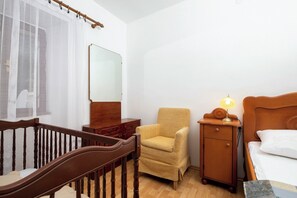 A bedroom with a wooden bed, a nightstand with a lamp, a chair, a dresser, and a mirror.
