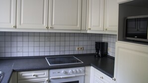 Een keuken met witte kastjes, een zwart aanrecht, een fornuis en een magnetron.