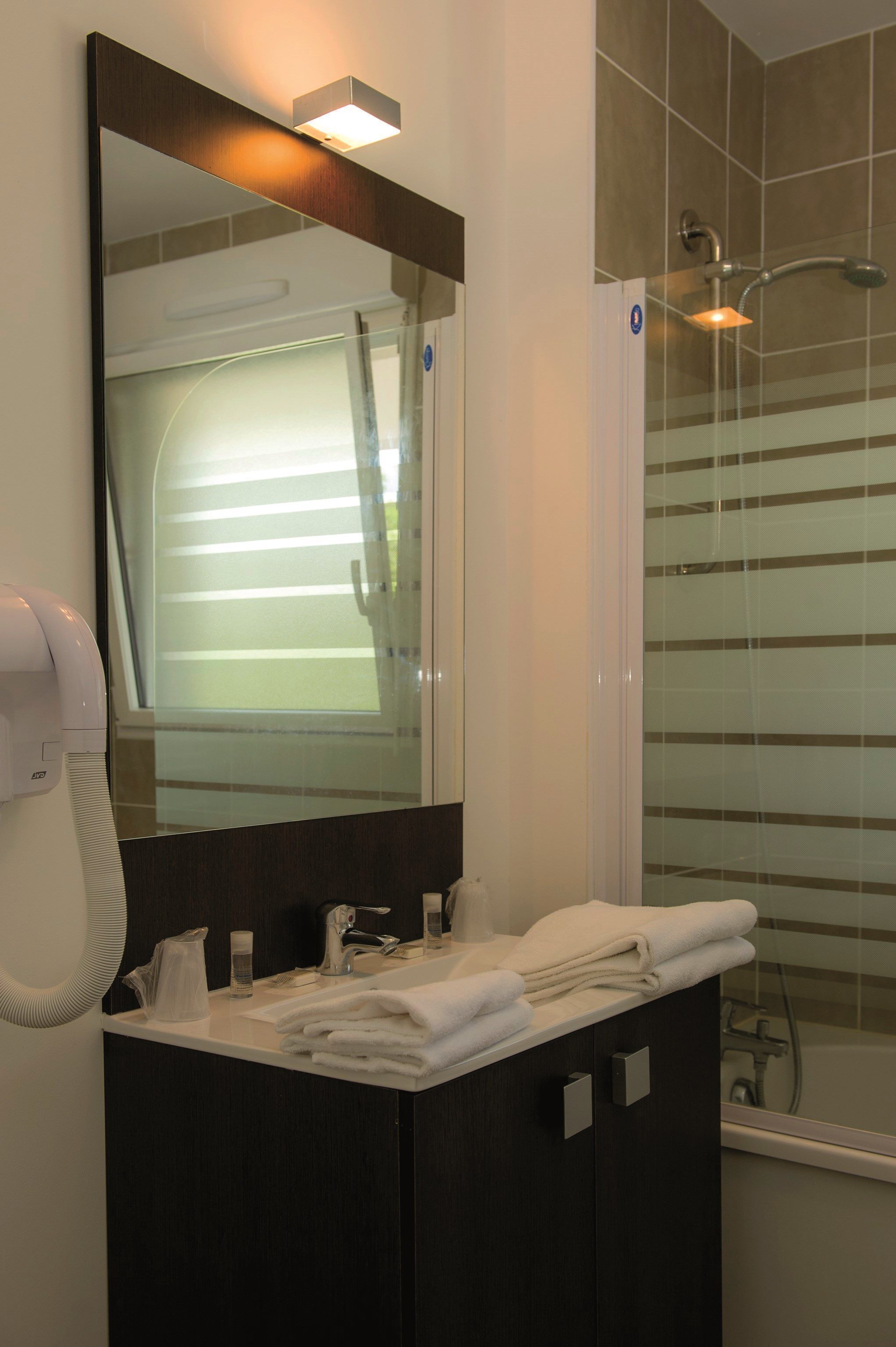 A bathroom with a large mirror, a sink, a towel rack, and a shower area.