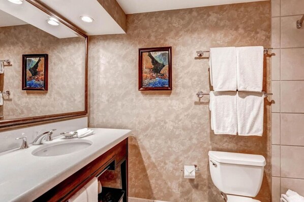 A bathroom with a double sink, a toilet, and two framed paintings on the wall.