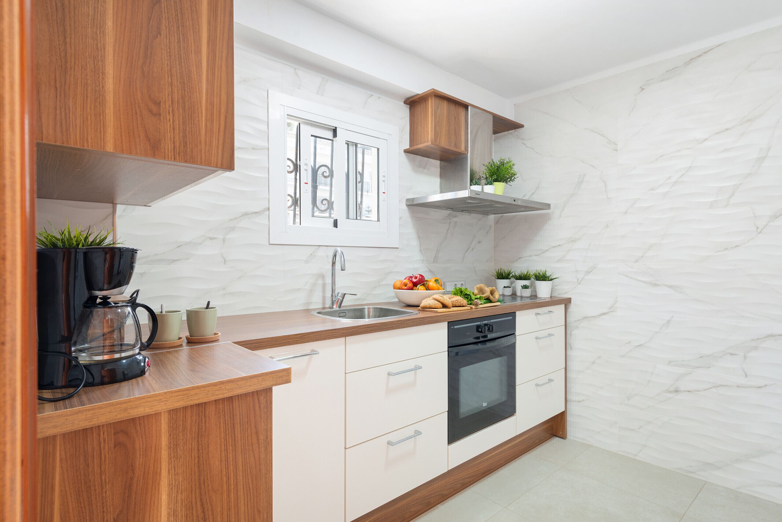 A modern kitchen with wooden cabinets, a built-in oven, and a window with decorative ironwork.