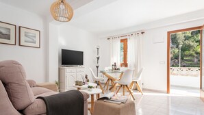Un salon moderne comprenant un canapé, un pouf et un coin repas avec une table et des chaises.