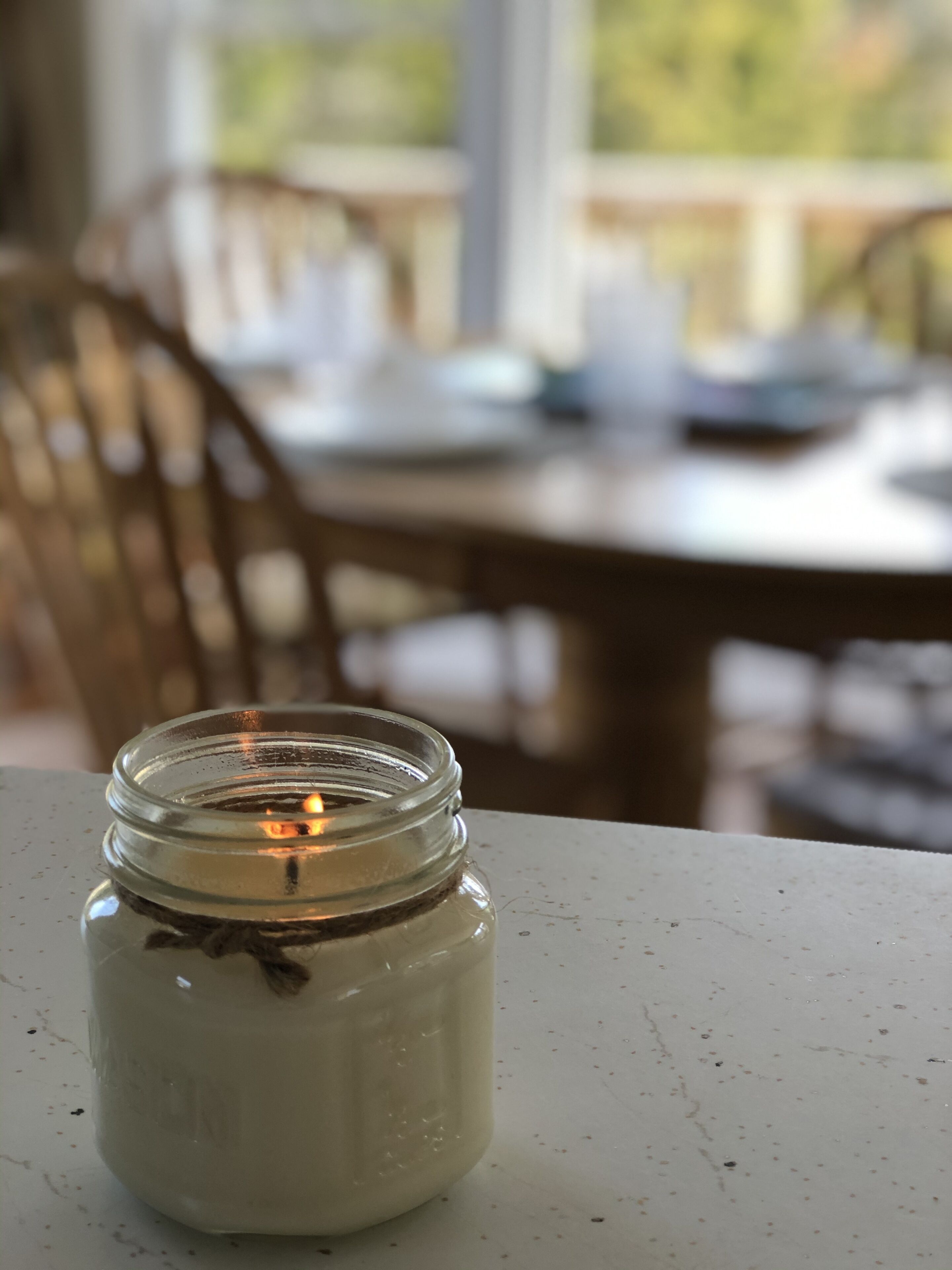 Une bougie dans un bocal, posée sur une table.