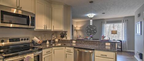 A modern kitchen with stainless steel appliances, white cabinetry, and a marble countertop.