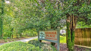 Schild für die Kanuga Place Eigentumswohnungen, umgeben von üppiger Vegetation und einem Holzzaun.