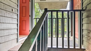 Eine Holztreppe mit Metallgeländer führt zu einer Veranda.