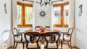 A dining room with a round table, six chairs, a chandelier, and decorative wall art. - Villa MIMOSA by Abahana Villas (Benitachell)