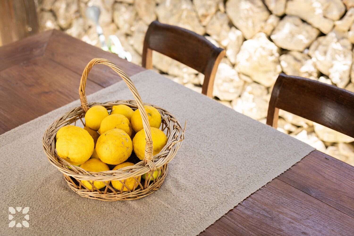 A wicker basket filled with lemons on a table with a beige placemat.