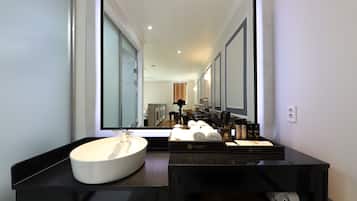 A modern bathroom with a large mirror, a white sink, and a black vanity.