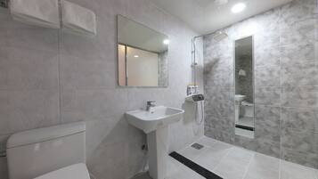Un baño moderno con inodoro blanco, lavamanos pedestal y zona de ducha.