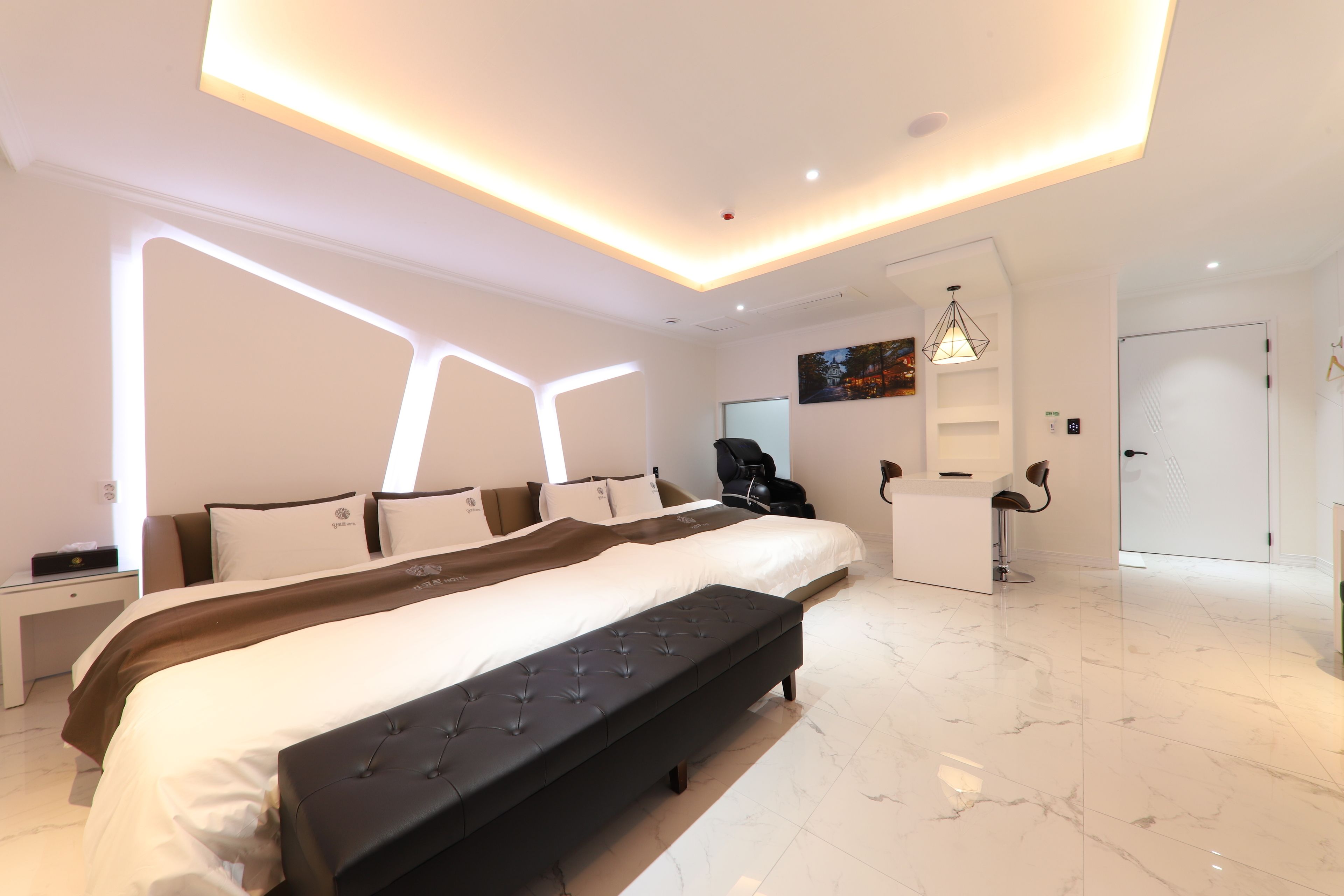 Habitación de hotel moderna con una cama grande, un banco, un escritorio y una silla.