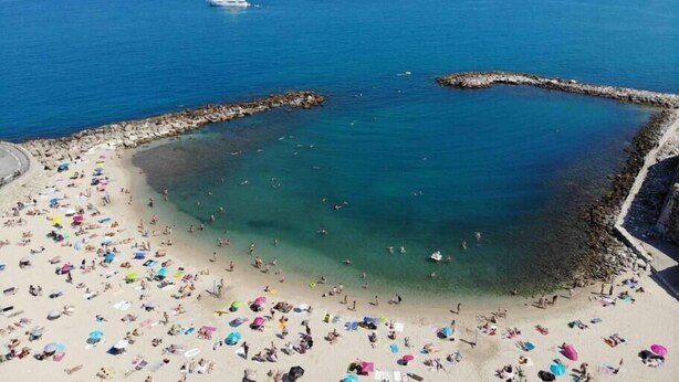 A beach with clear waters, a rocky breakwater, and several boats in the distance. - Spacious new one-bedroom apartment in the heart of the Old Town (Antibes)