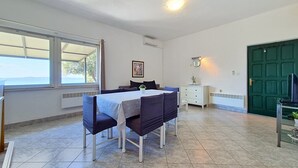 A room with a dining table, chairs, a bed, a window, a door, and a radiator. - Holiday house Selak * large garden, terrace, sea view, free WiFi (Tucepi)