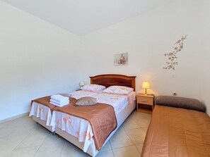 A single bed with a wooden headboard, a nightstand with a lamp, and a wall-mounted picture. - Holiday house Selak * large garden, terrace, sea view, free WiFi (Tucepi)