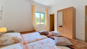 A hotel room with two beds, a wardrobe, a window with curtains, and a lamp. - Holiday house Selak * large garden, terrace, sea view, free WiFi (Tucepi)