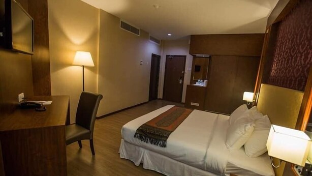 A hotel room with a bed, a desk, a chair, a TV, and a lamp. - Hotel Pen Mutiara (George Town)
