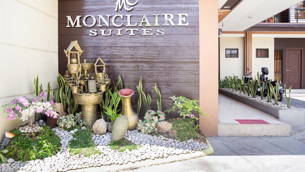 A hotel entrance with a sign reading "MONCLAIRE SUITES" and a decorative garden with plants and rocks. - OYO 153 Espacio de Clarita Hometel (Davao)