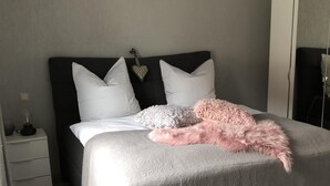 Una camera da letto con un letto, un comodino, un armadio e uno specchio.