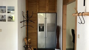 Una cucina con frigorifero in acciaio inossidabile, pensili in legno, una sedia nera e una panca in legno.