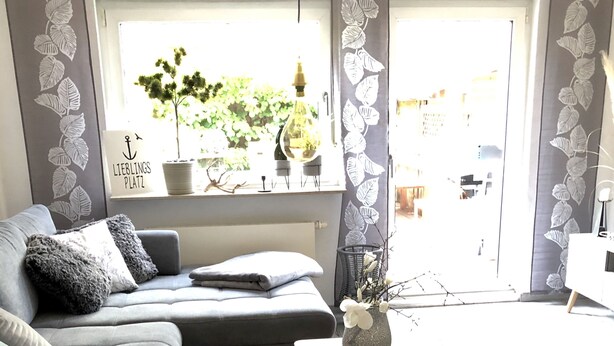 Un soggiorno moderno con un divano grigio, un piccolo tavolino in legno e un pouf grigio.