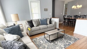 Ein Wohnzimmer mit grauem Sofa, Couchtisch und einem gemusterten Teppich.