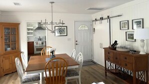 Ein Essbereich mit Holztisch und -stühlen, einer Kronleuchter und einer Küche im Hintergrund.