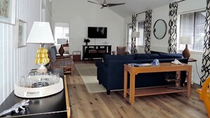 Ein modernes Wohnzimmer mit einer Couch, einem Couchtisch, einem Fernseher und einem Deckenventilator.