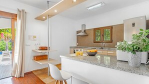 A modern kitchen with a central island, a built-in oven, and a stainless steel refrigerator. - Villa FUMEPACOON by Abahana Villas (Benissa)