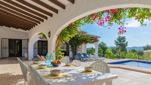 A dining area with a pool view, white furniture, and a pergola with flowers. - Villa FUMEPACOON by Abahana Villas (Benissa)