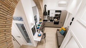 Une cuisine moderne avec des meubles blancs, une hotte noire et un coin repas comprenant une table et des chaises.