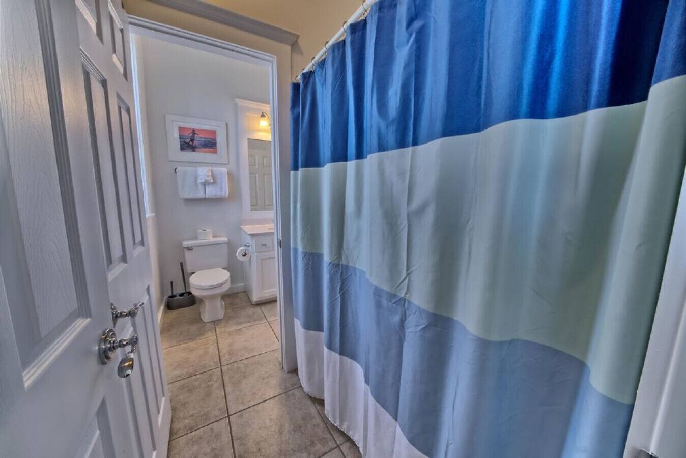 Casa de banho com sanita branca, lavatório e cortina de chuveiro.