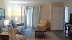 Ein Wohnzimmer mit einer Couch, Sesseln, einem Couchtisch und einer TV-Konsole.