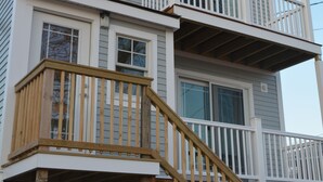 Ein zweigeschossiges Haus mit einer Holztreppe, die zu einem Balkon führt.