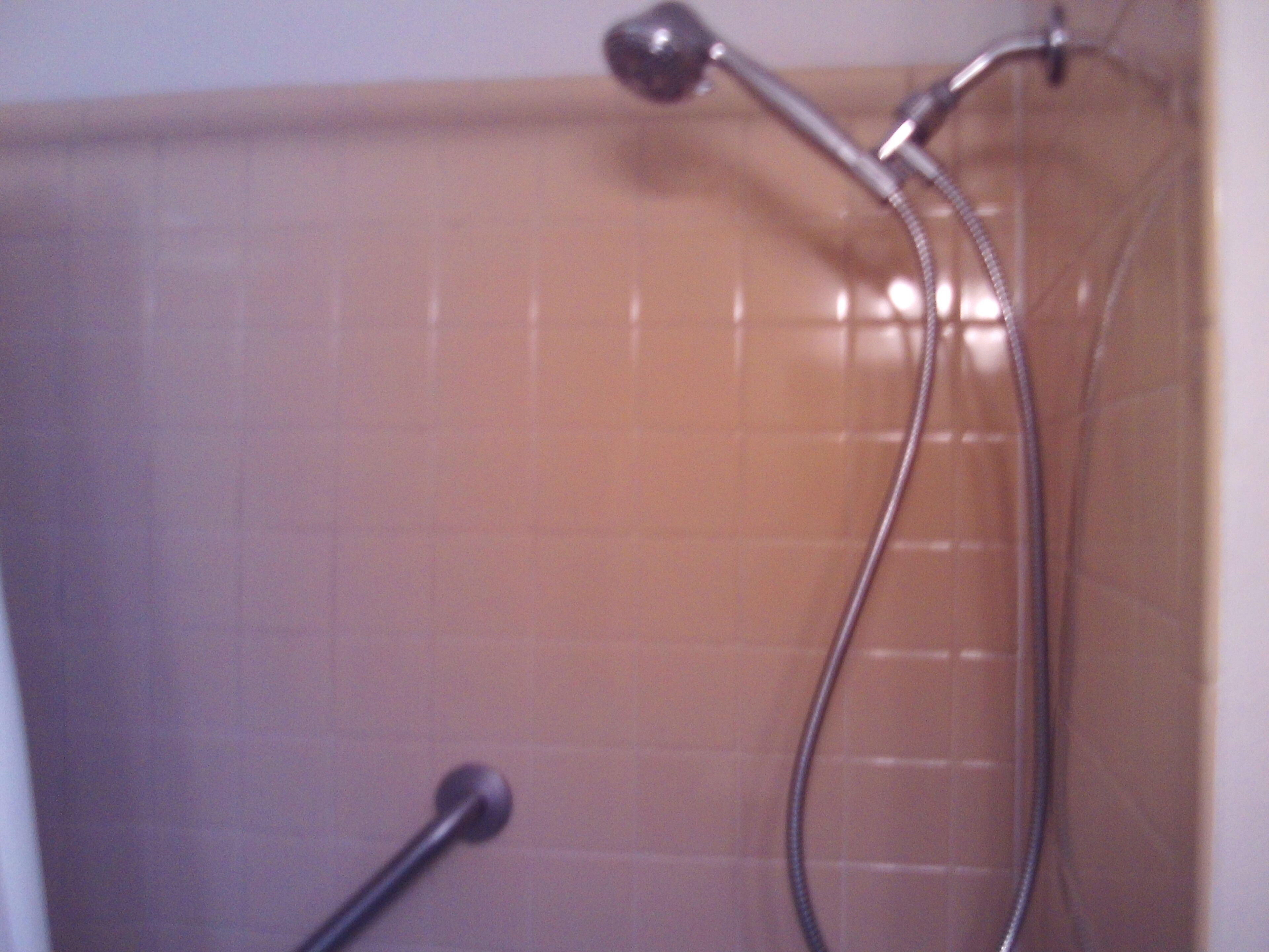 A shower with a handheld showerhead and a fixed showerhead.