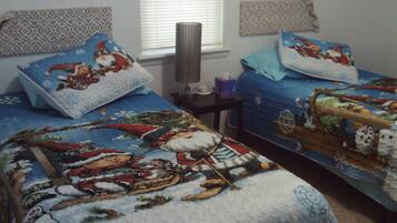 Cozy retreat with two beds, a table, and a lamp, perfect for a comfortable stay.