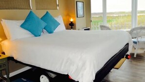 Habitación de hotel con una cama grande, una mesita de noche, una lámpara y vistas al exterior.