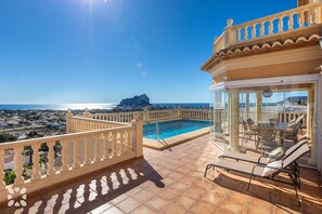 Una terraza en la azotea con piscina, mobiliario exterior y vistas a la costa.