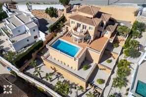 Une grande maison avec une piscine, plusieurs balcons et une cour intérieure.