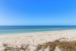A beach with clear blue water and a sandy shore.